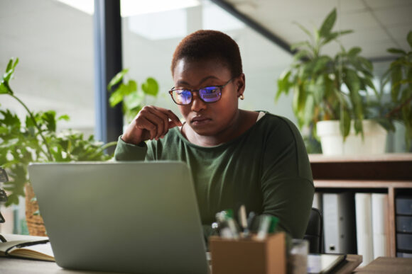 Woman looking at computer with a thoughtful expression.