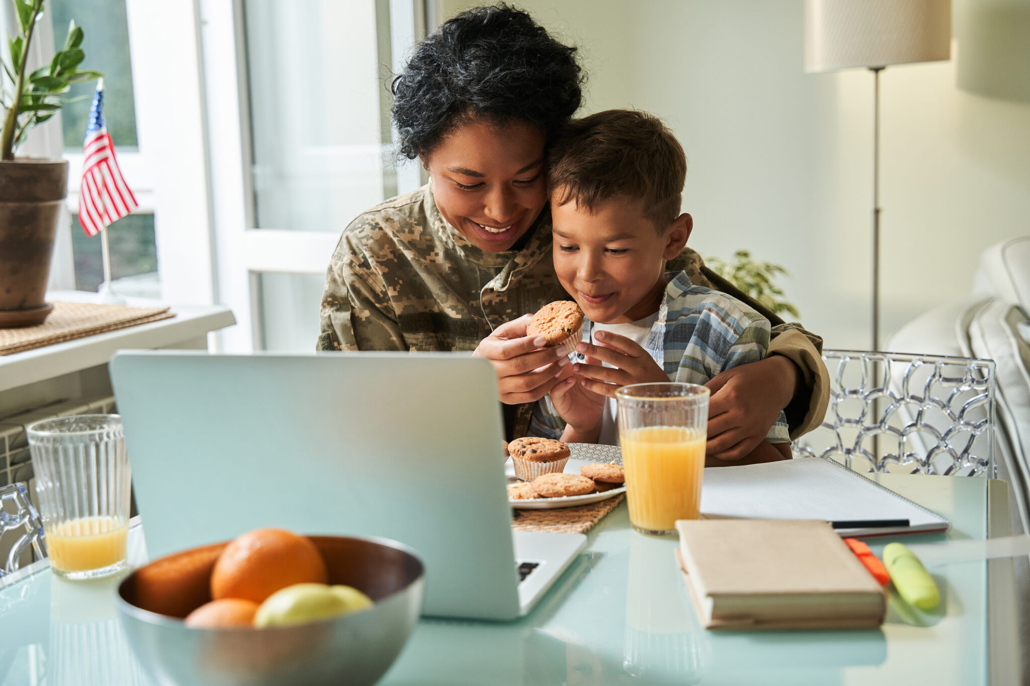 Woman in camouflage uniform feeding her son breakfast.