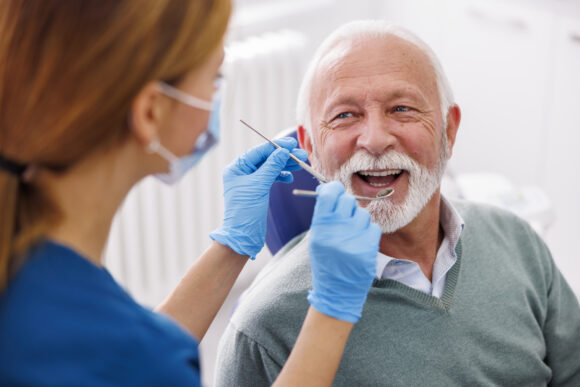 Senior man in a dentist chair talking with the dentist.