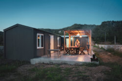 Homeowner and child on patio in front of a tiny home, setting a table for dinner.