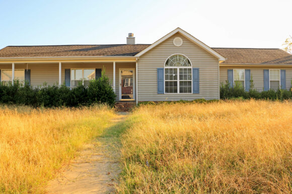 Modest foreclosed home with tall, uncut grass